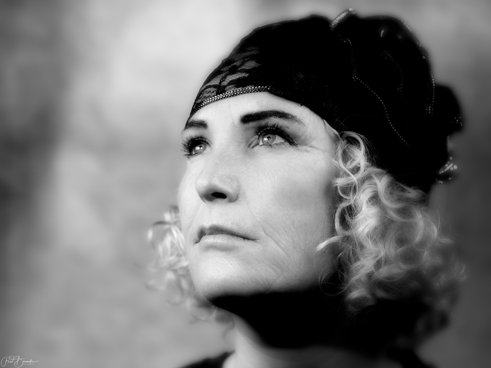A close-up view of a person with curly hair and a dark head covering, looking slightly to the side.