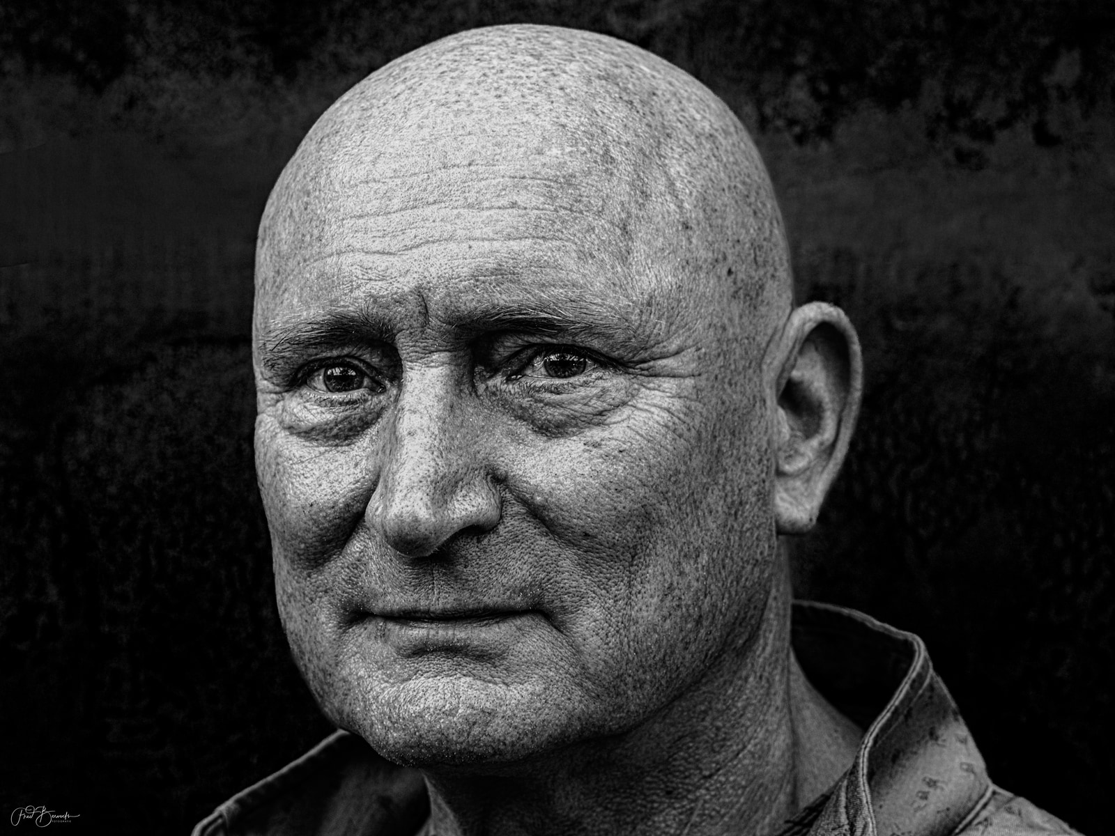 A close-up portrait of an older man with a serious expression, captured in black and white.