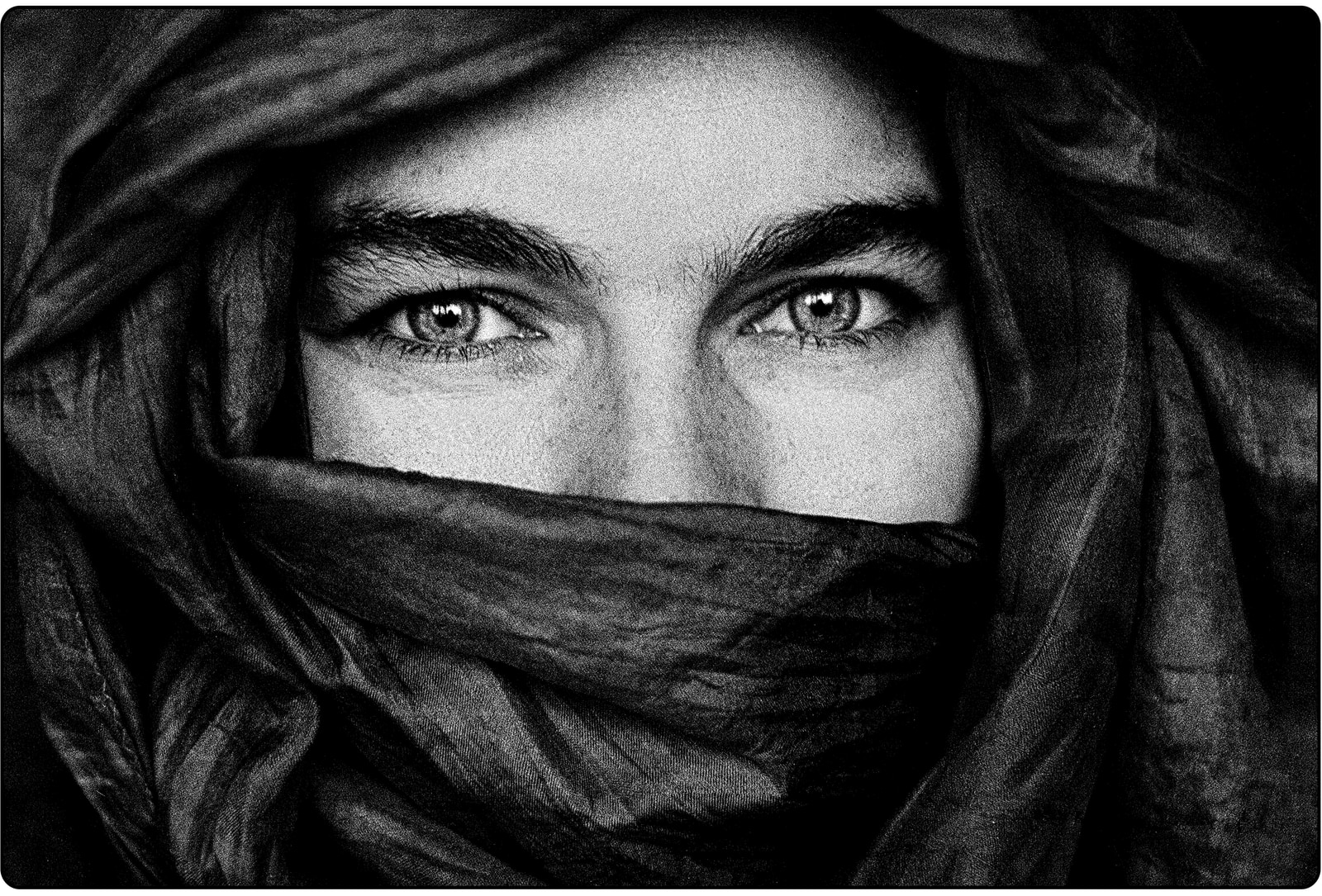 A close-up view shows a person's eyes and the fabric of a head covering.