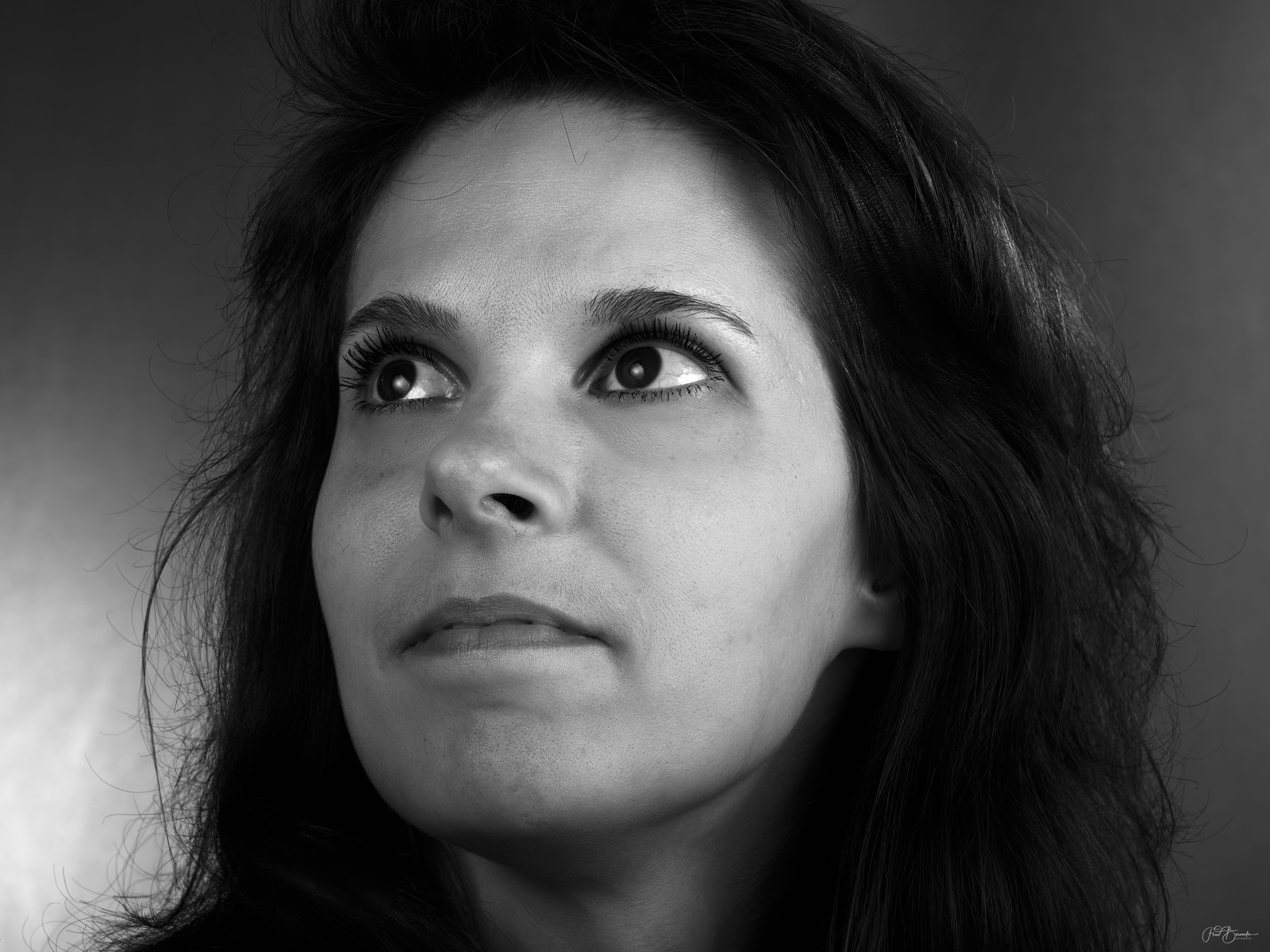 A close-up portrait of a person with long hair, looking directly at the camera.