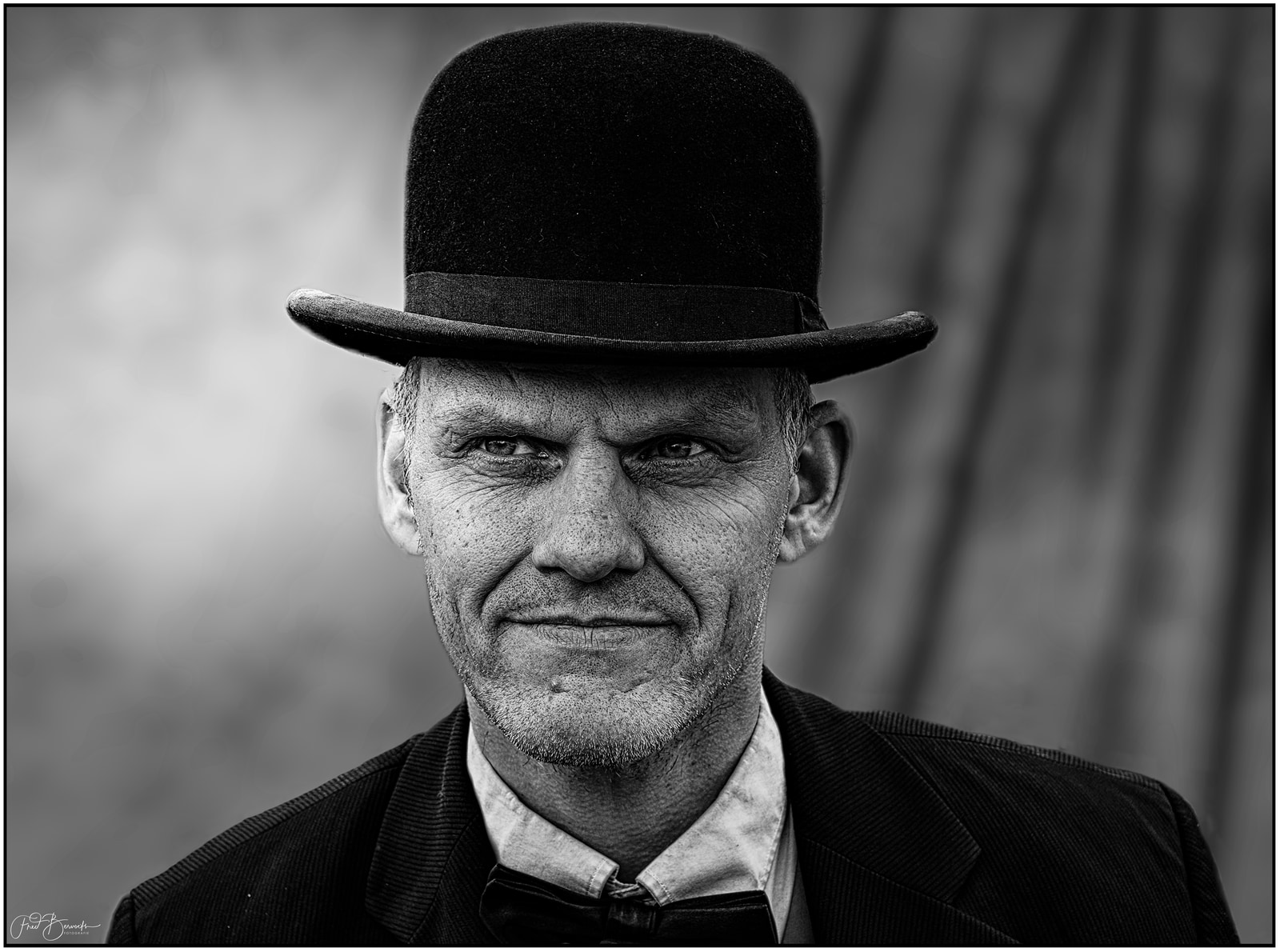 An older man in formal attire, including a top hat and suit, poses for a portrait.