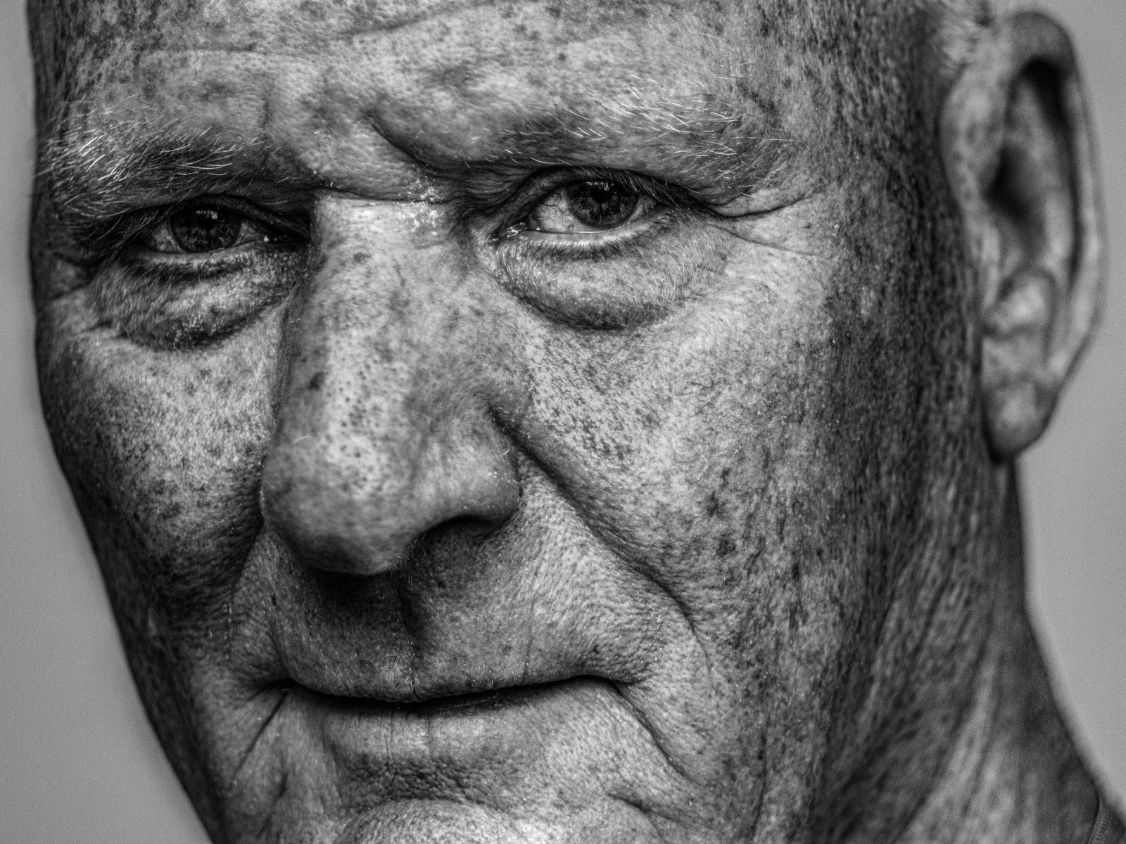 An elderly man with closed eyes and a calm expression, captured in a close-up portrait.